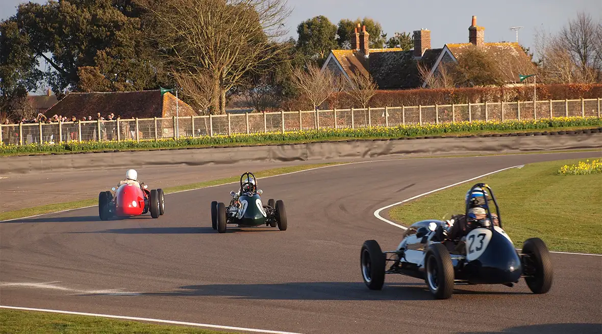 Trois voitures de course des années 50 se poursuivent sur un circuit
