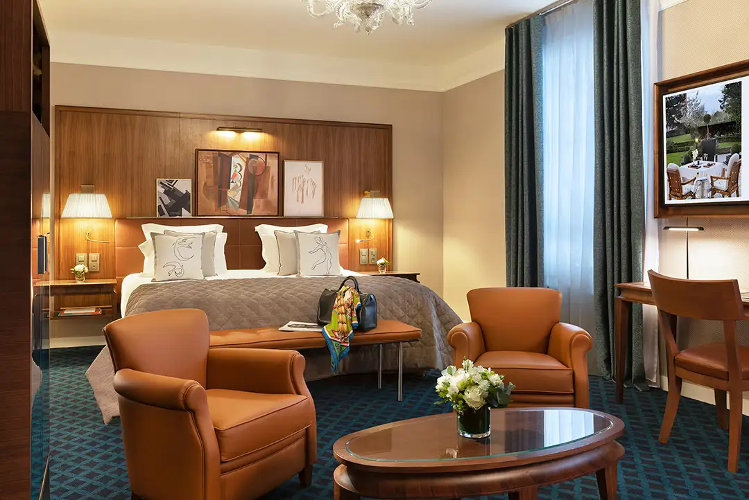A luxurious room with a coffee table, armchairs and bed at the 5* Hôtel Barrière Le Westminster, in Le Touquet.