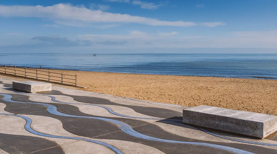 Promenade avec motifs de vagues au sol longeant la plage de sable doré et la bleu profond à Ramsgate