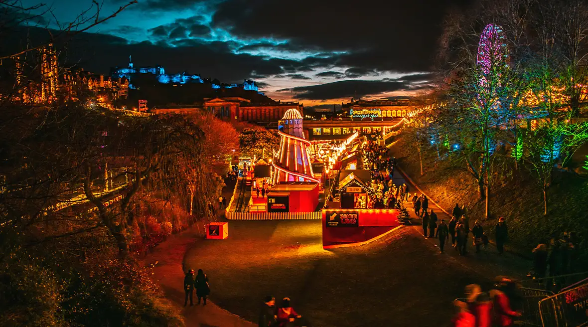 Manèges et chalets du marché de Noël sur une place d’Edimbourg au crépuscule