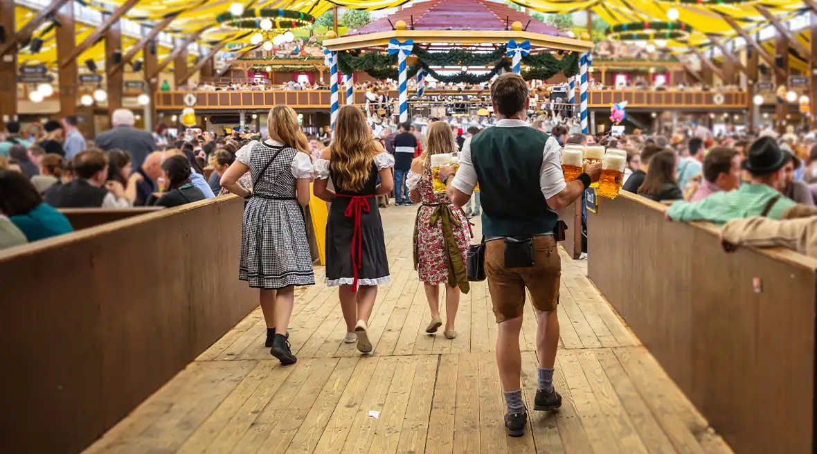 People walking through a decorated beer tent carrying beer at Oktoberfest, Munich