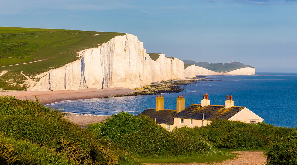 Une maison au bord de la mer devant des falaises de craie blanche