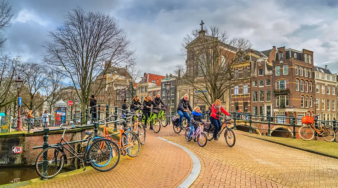 Cityscape on a sunny winter day - view on the group of cyclists in the historic center of Amsterdam, The Netherlands