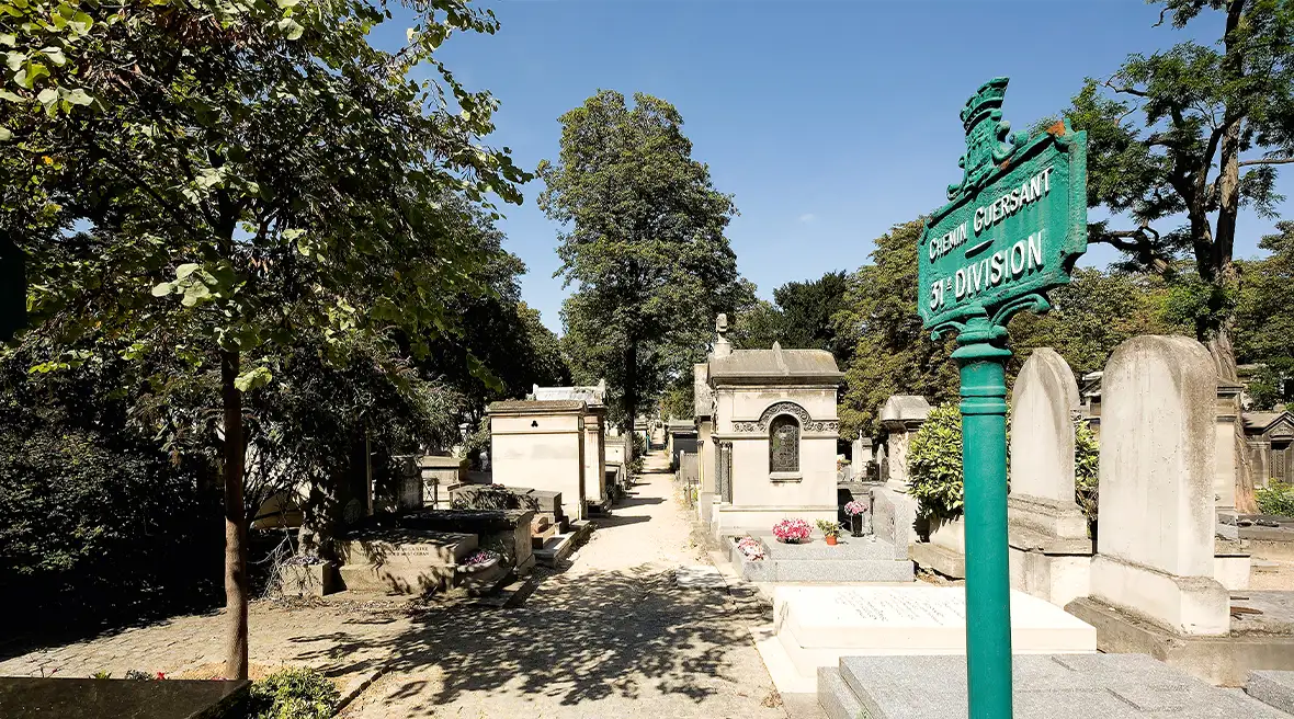 A bright sunny day in the Montmartre cemetery. A green ‘road’ sign reads Chemin Guersant, 31eme division