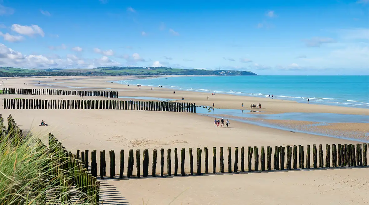 A view of Wissant beach and it’s groin fences at low tide, the sea is miles out and there are people walking and flying kites