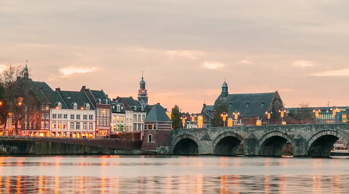 View of a Dutch bridge with lights over river with Dutch architecture
