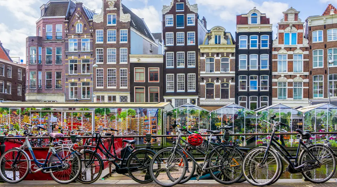 Pretty Dutch buildings along street by river with lots of bicycles against railings