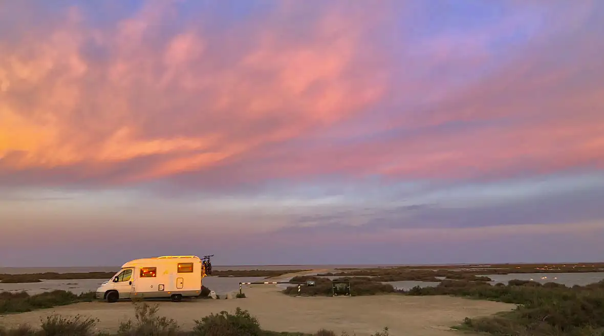 A lone motorhome looks out at a beautiful sunset