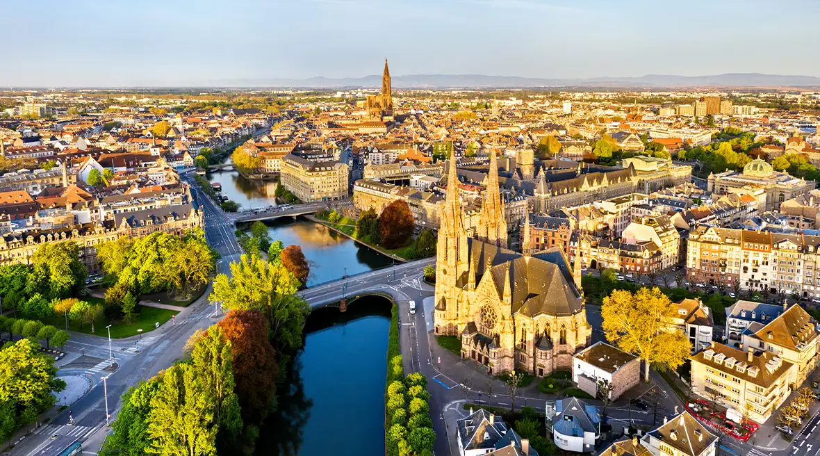 View over a city with a river running through it with a large cathedral and trees lining the riverbanks