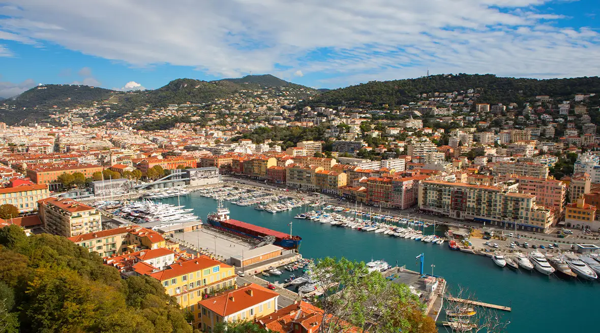 A view of a colourful port with boats in the harbour and mountains in the distance