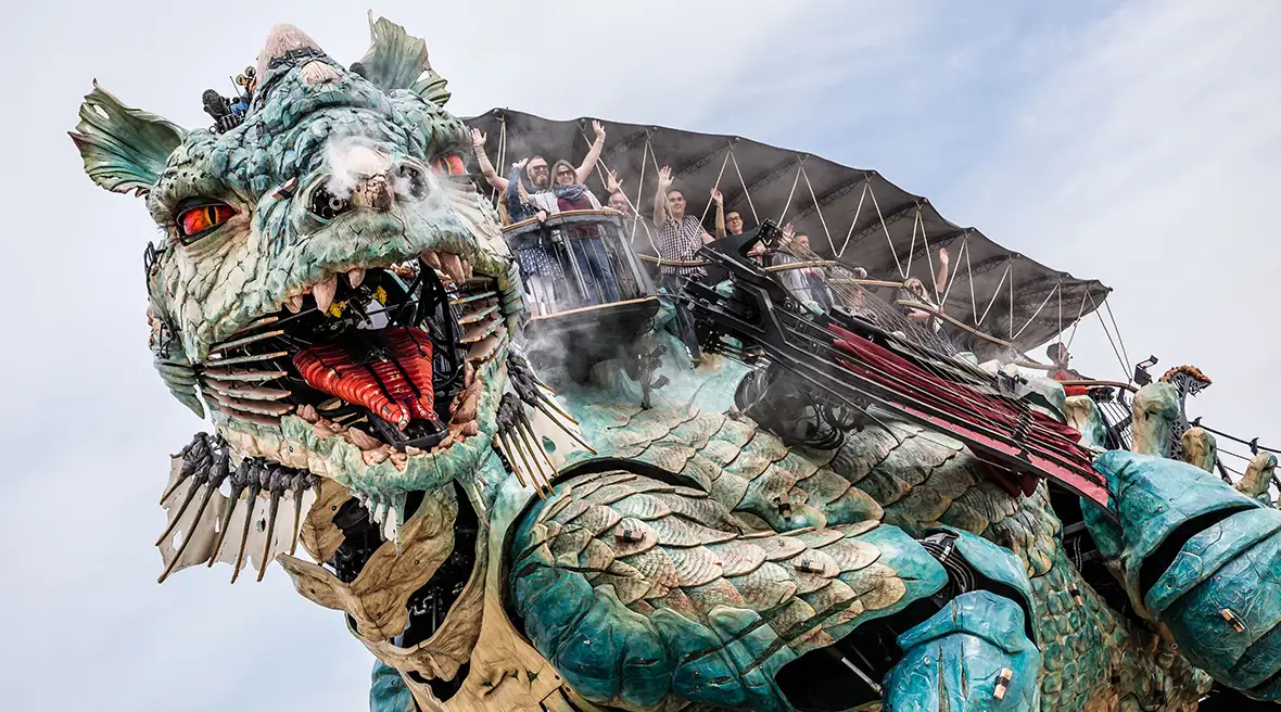 The face of the huge mechanical dragon looks down at the camera, its mouth open and teeth bared