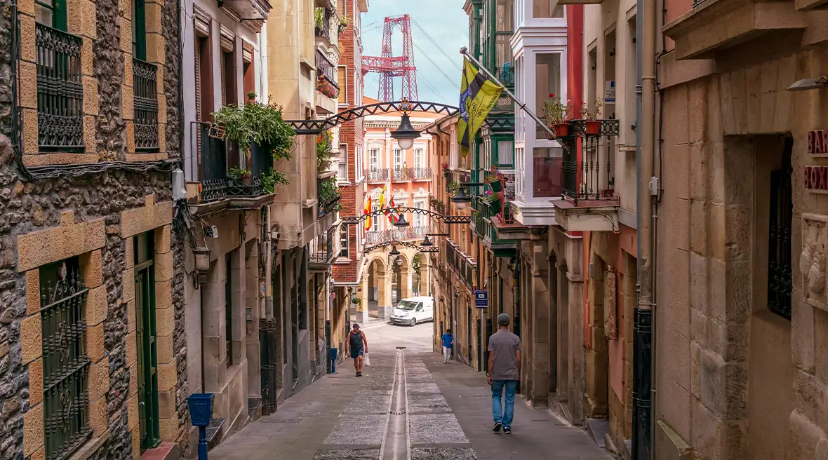 A long Spanish street lined with houses leading towards a sunny square