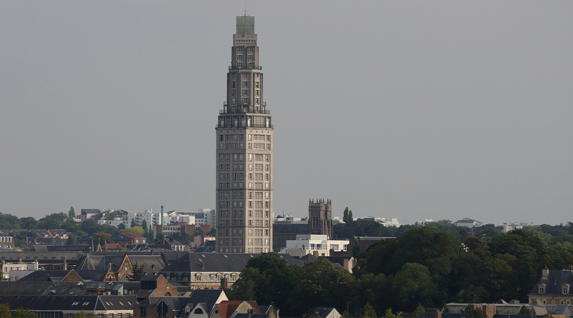 Tour Perret against a grey sky with houses and treetops surrounding it