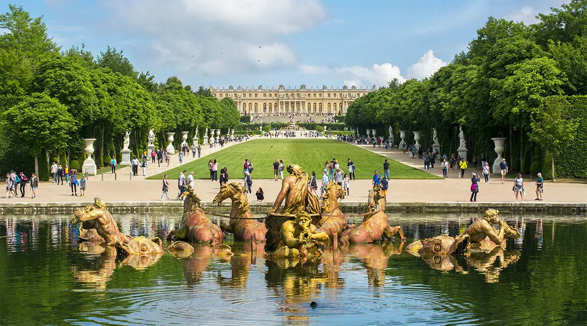 Bronze statue of a classical god and horses in a fountain in the gardens of a grand palace