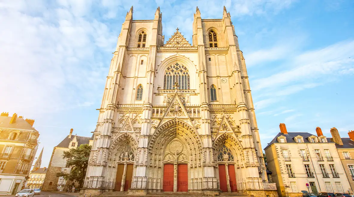 large gothic building with red doors towering into the blue skyline