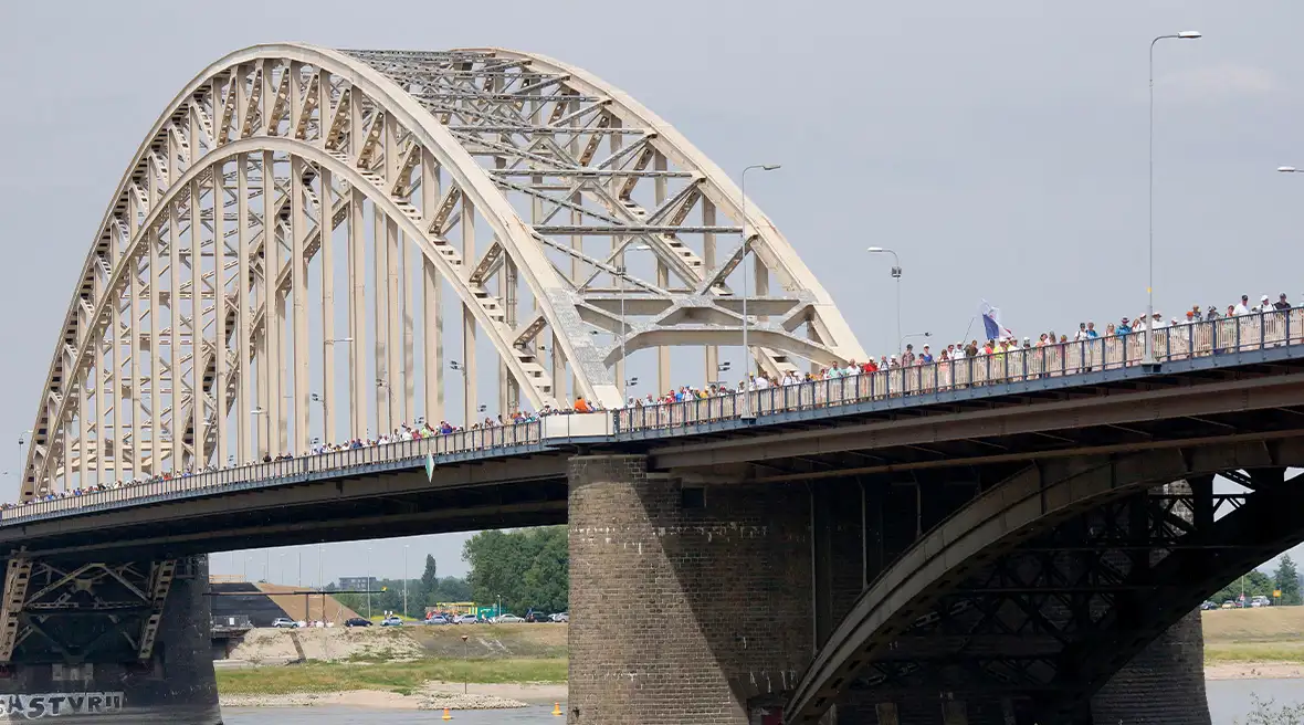 Arched bridge over a river with crowds of people walking over it