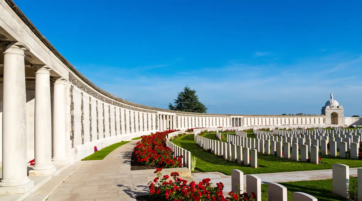 Lines of gravestones in circular rows at a large memorial cemetery, with deep blue sky in the background
