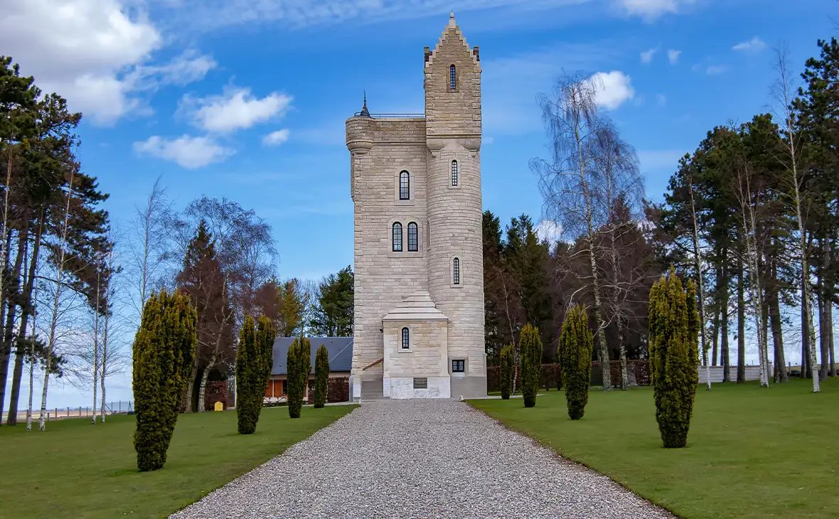 White stone tower at the end of a footpath against a blue sky