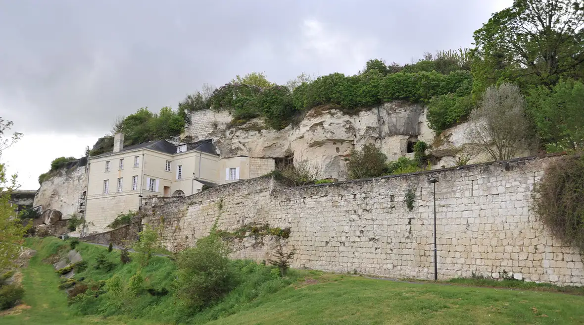 A house built into a cliffside with a high brick wall below