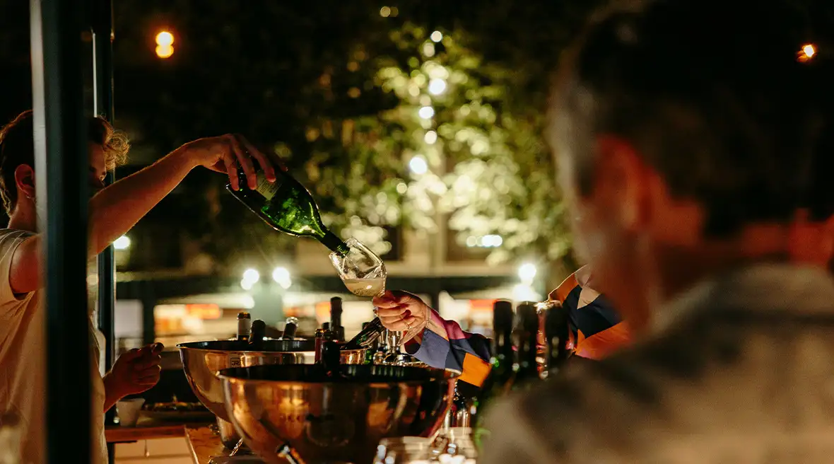 Group of friends pouring a glass of wine on a Paris street