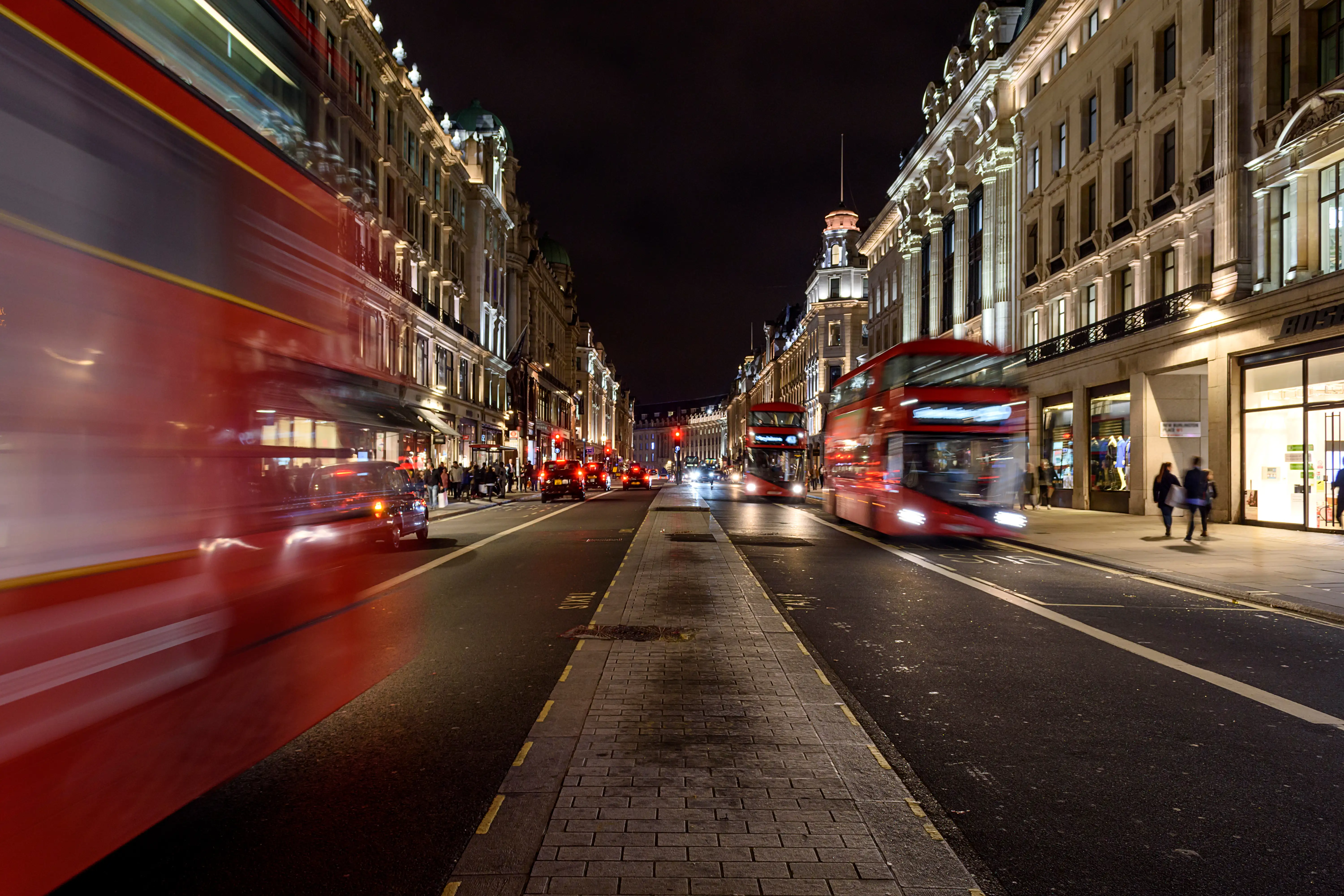 Regent Street à Londres, de nuit, avec des magasins illuminés et une foule animée