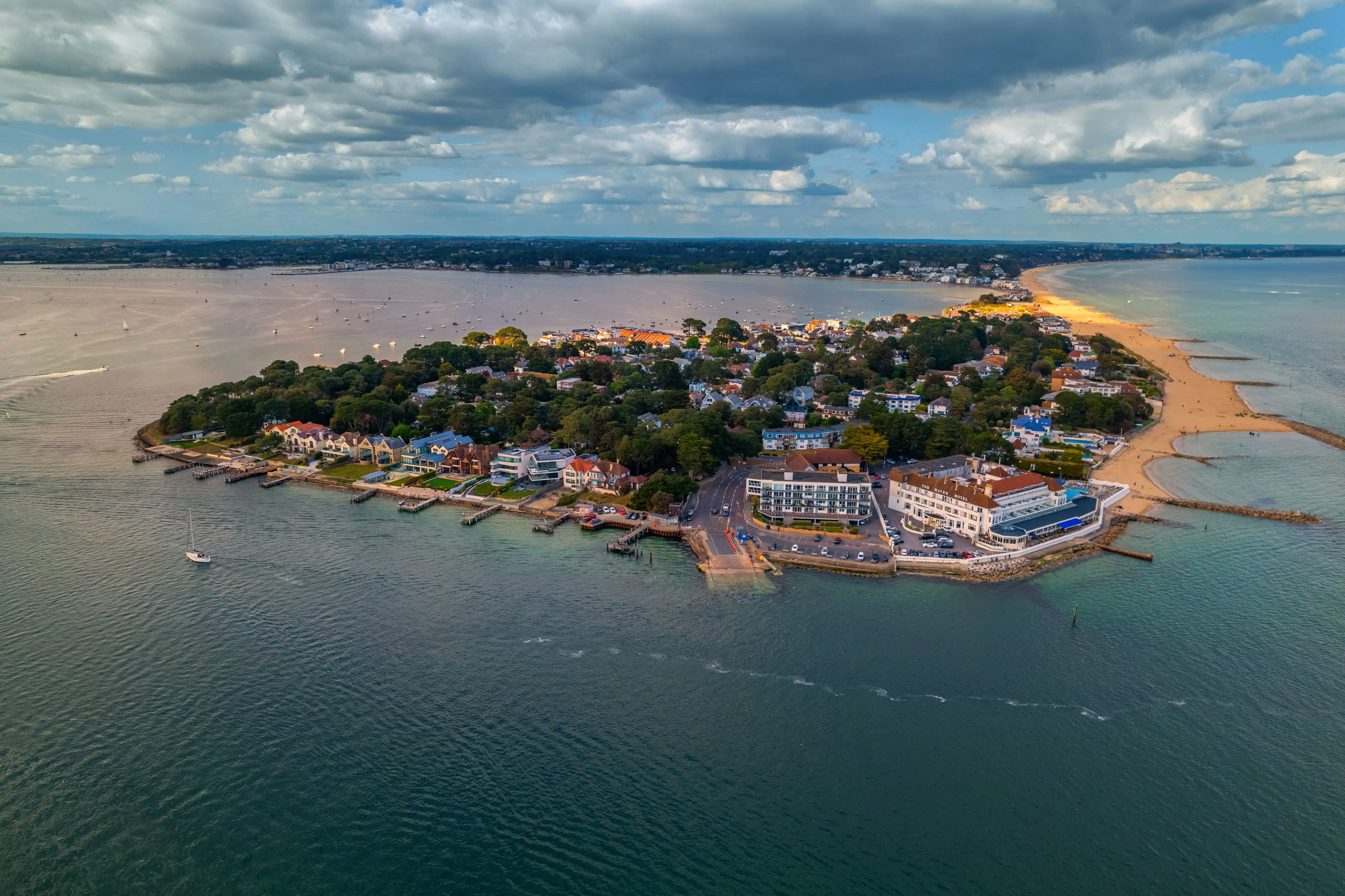 Péninsule avec une plage de sable, des maisons sur la côte et de la verdure