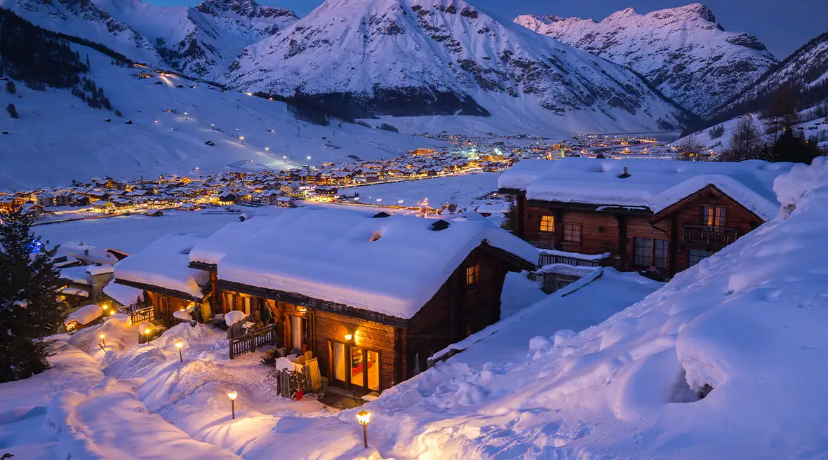 Snow-covered chalets and an Alpine village at dusk