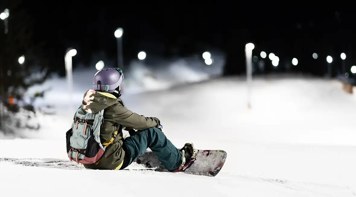 Snowboarder on the slopes under floodlights
