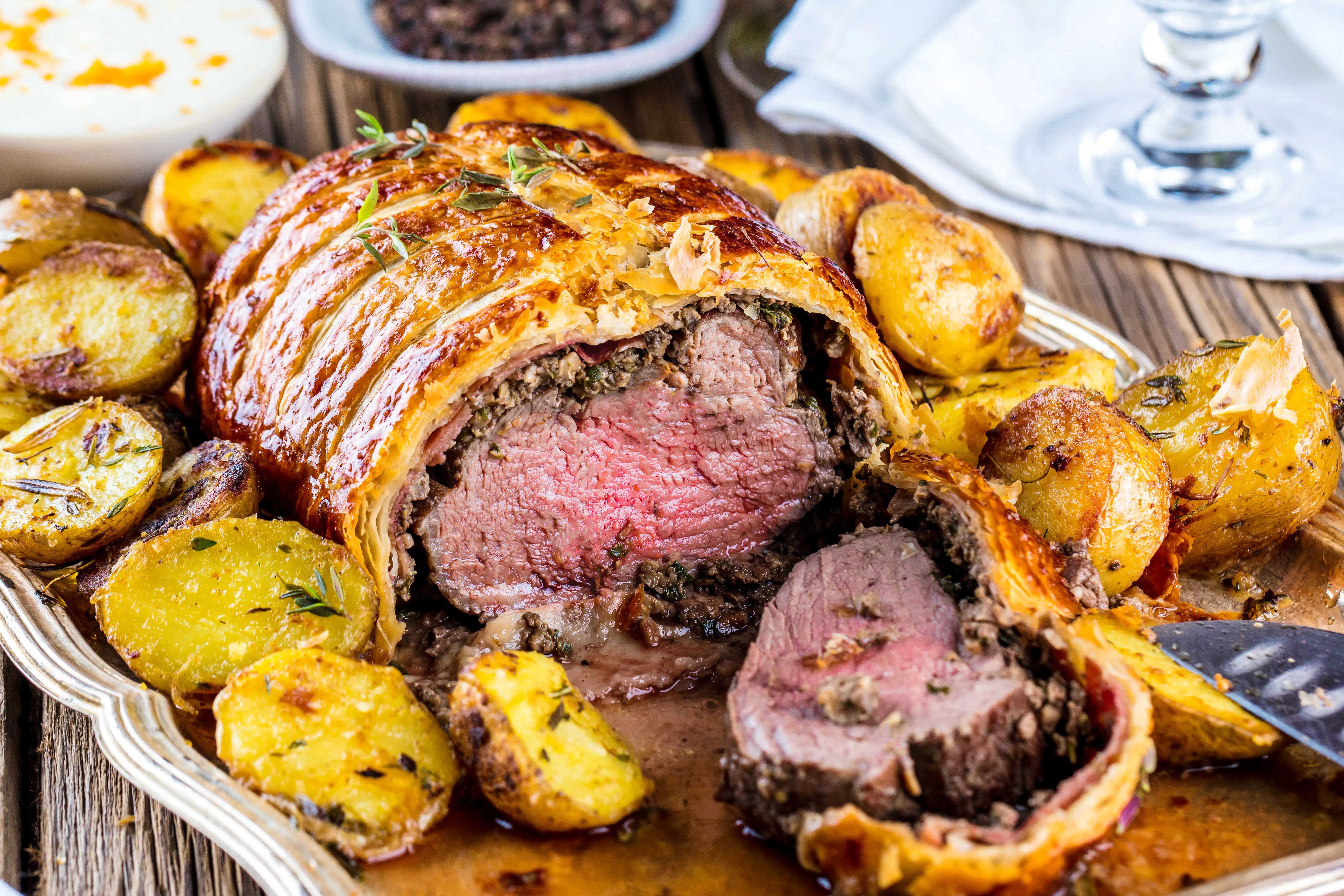 Beef Wellington met een perfect gebakken ossenhaas in goudbruin bladerdeeg, in plakjes gesneden zodat de roze kern zichtbaar is.