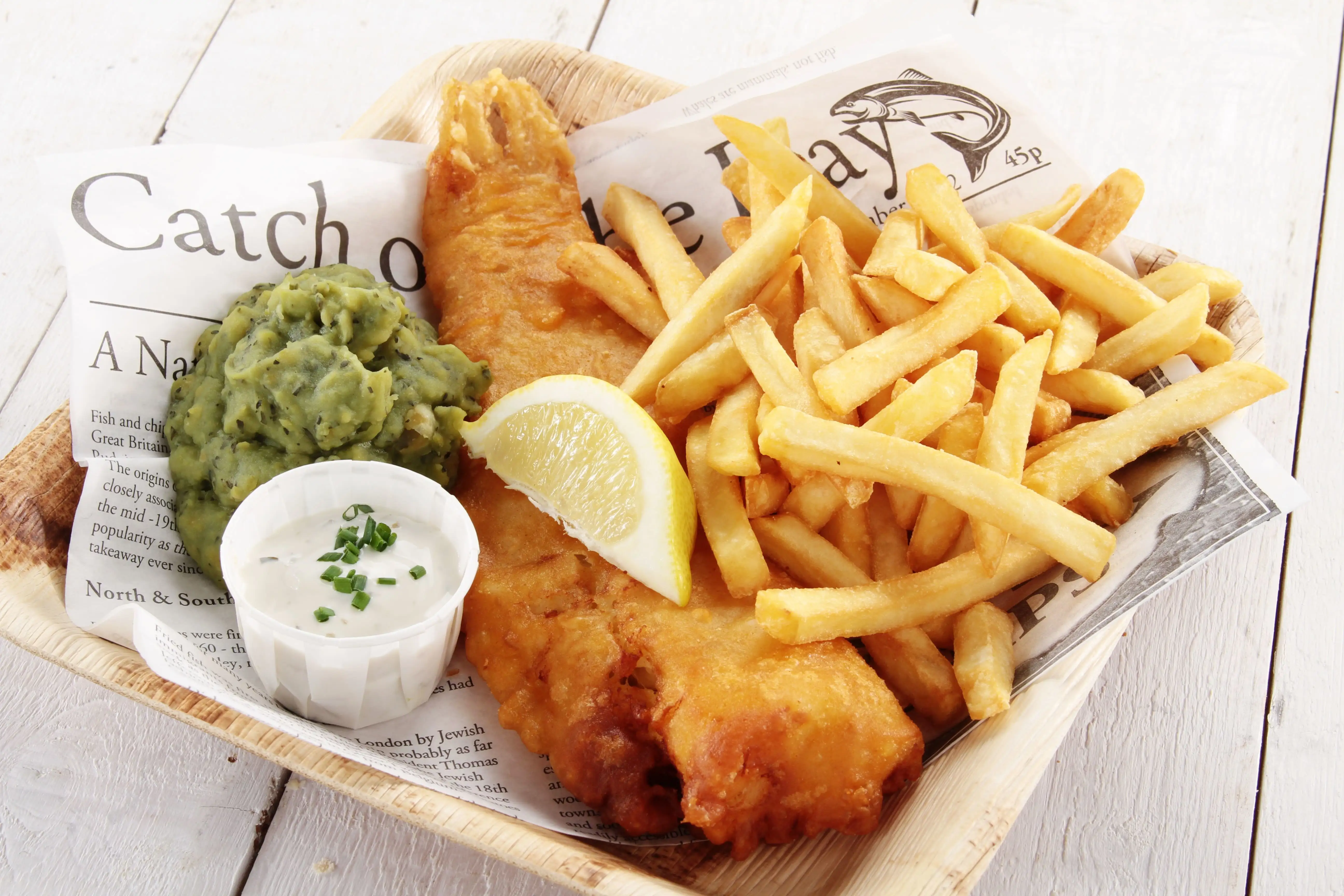 Traditionele fish and chips geserveerd met erwtenpuree en tartaarsaus.