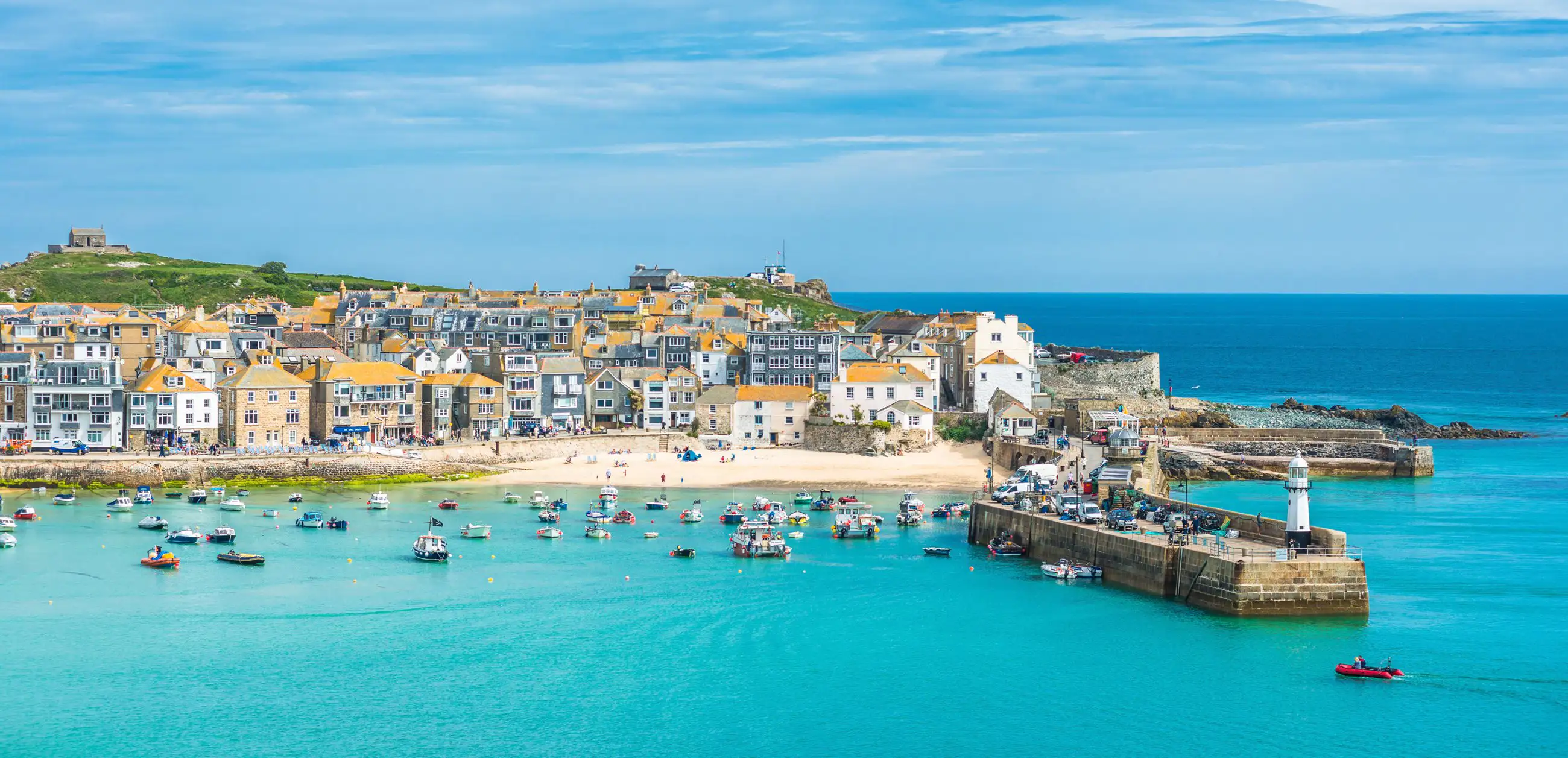 Vue surélevée de St Ives, dans les Cornouailles, avec ses plages ensablées, ses eaux turquoise et sa station balnéaire animée.