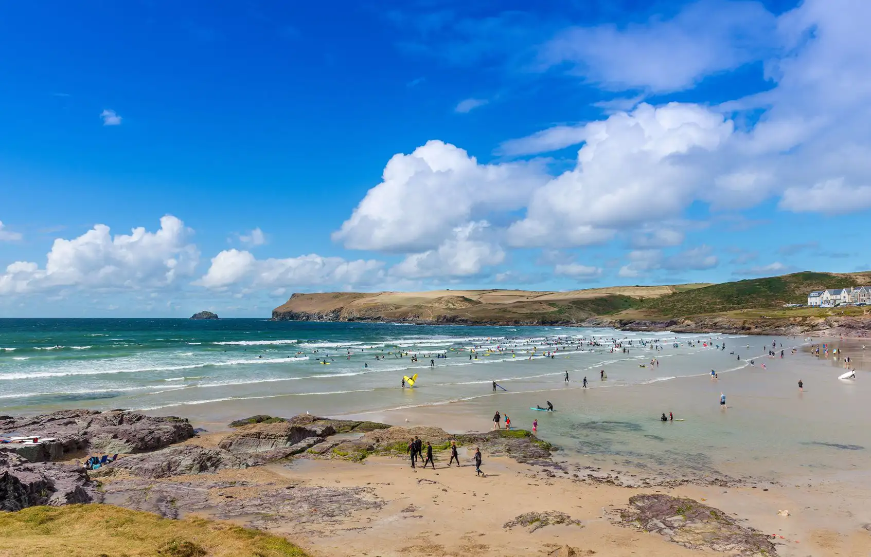 Surfer und Schwimmer im Meer am Strand von Polzeath, Cornwall.