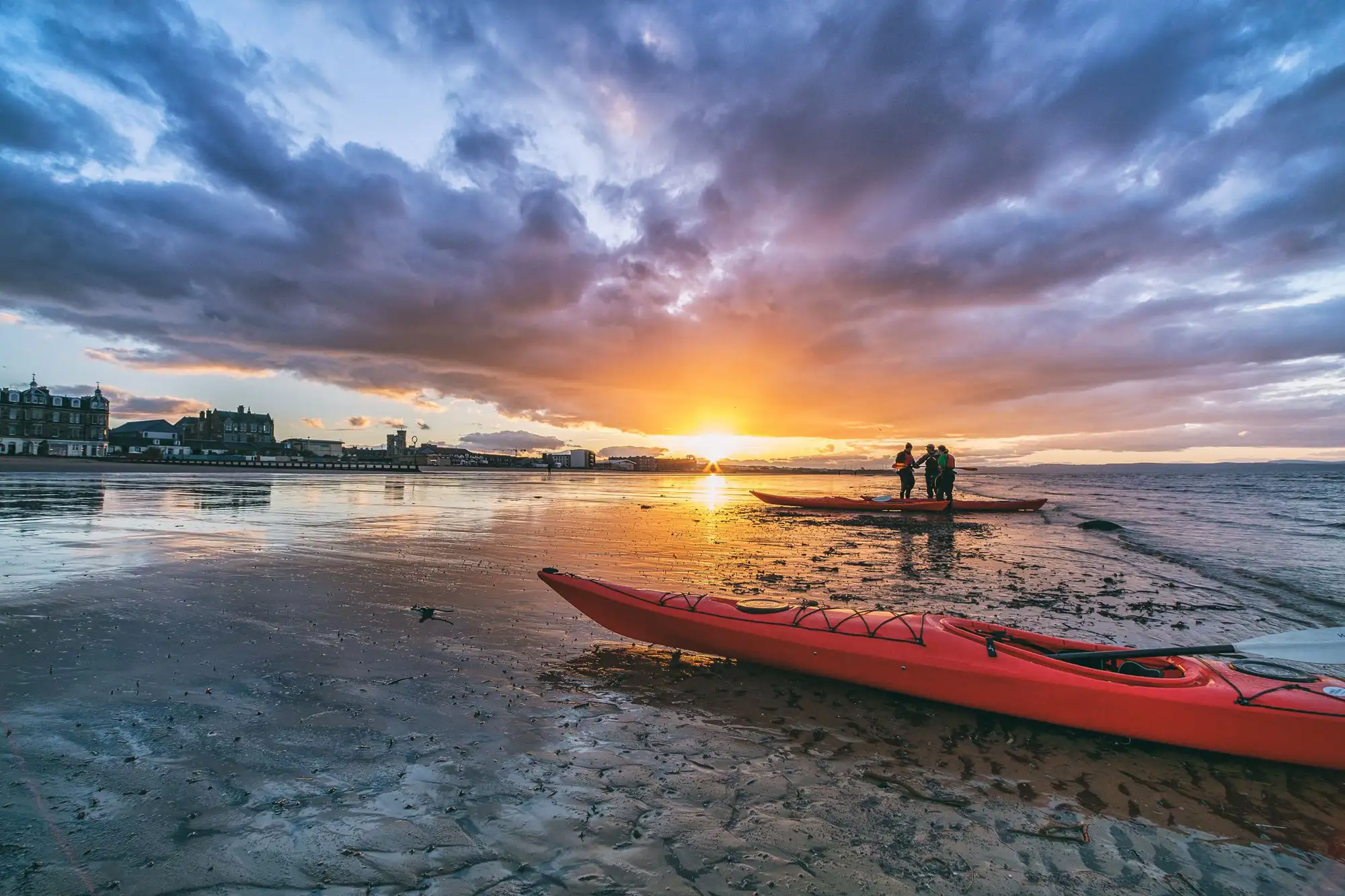 Kayaks et kayakistes sur une plage au coucher du soleil