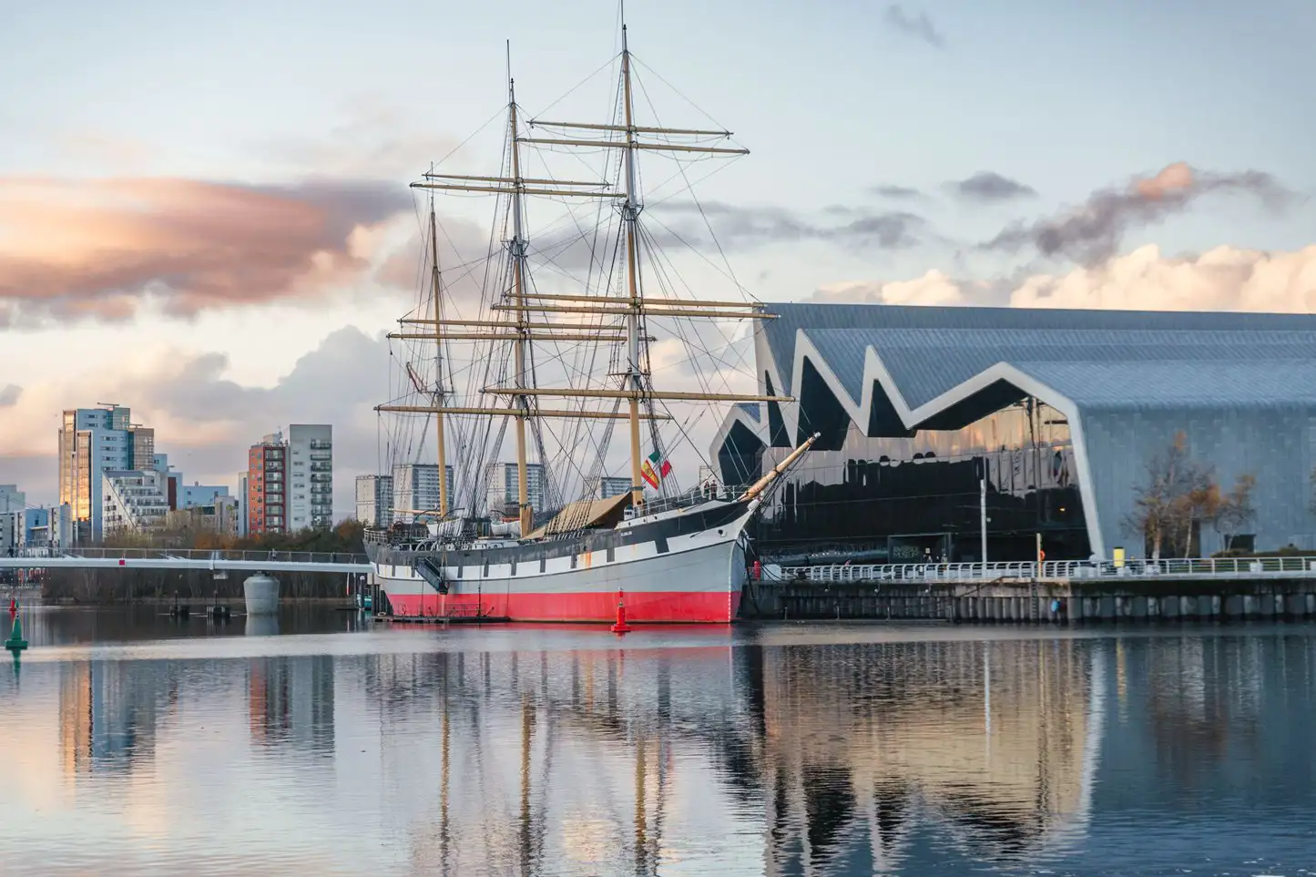 Een futuristisch gebouw en een grootzeilschip aangemeerd in Glasgow.