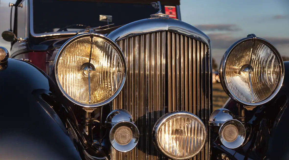 Nahaufnahme eines Oldtimer-Bentleys mit eingeschalteten Scheinwerfern