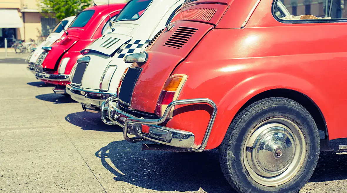 Rückansicht einer Reihe von Oldtimern, die beim Goodwood Festival auf dem Rasen geparkt sind.