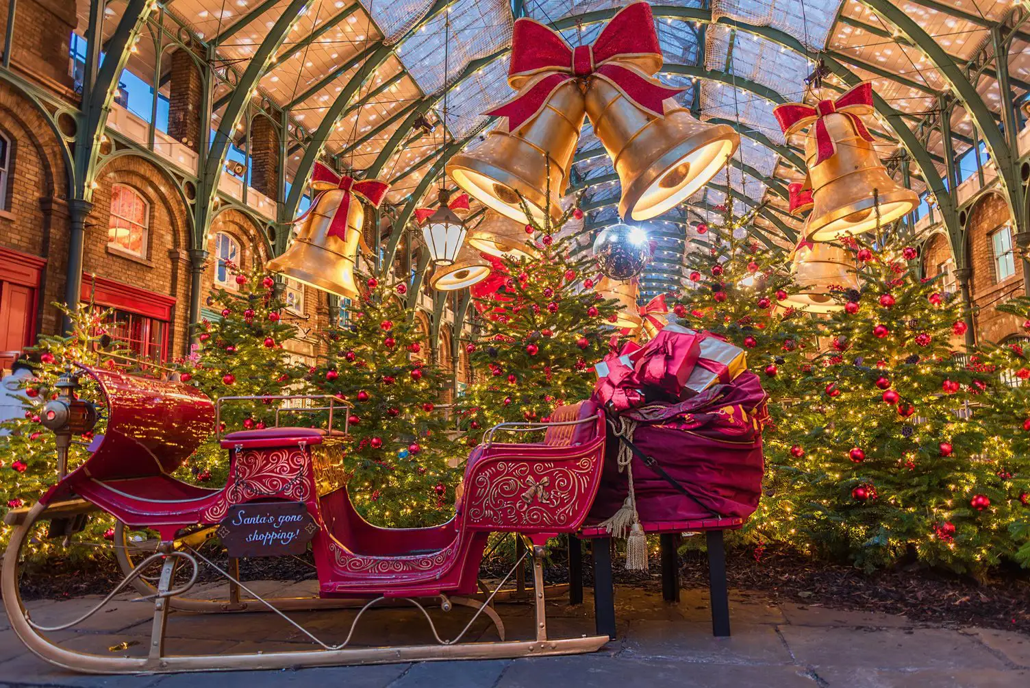 Kerstbomen, grote versierde kerstklokken en een slee, Covent Garden, Londen.