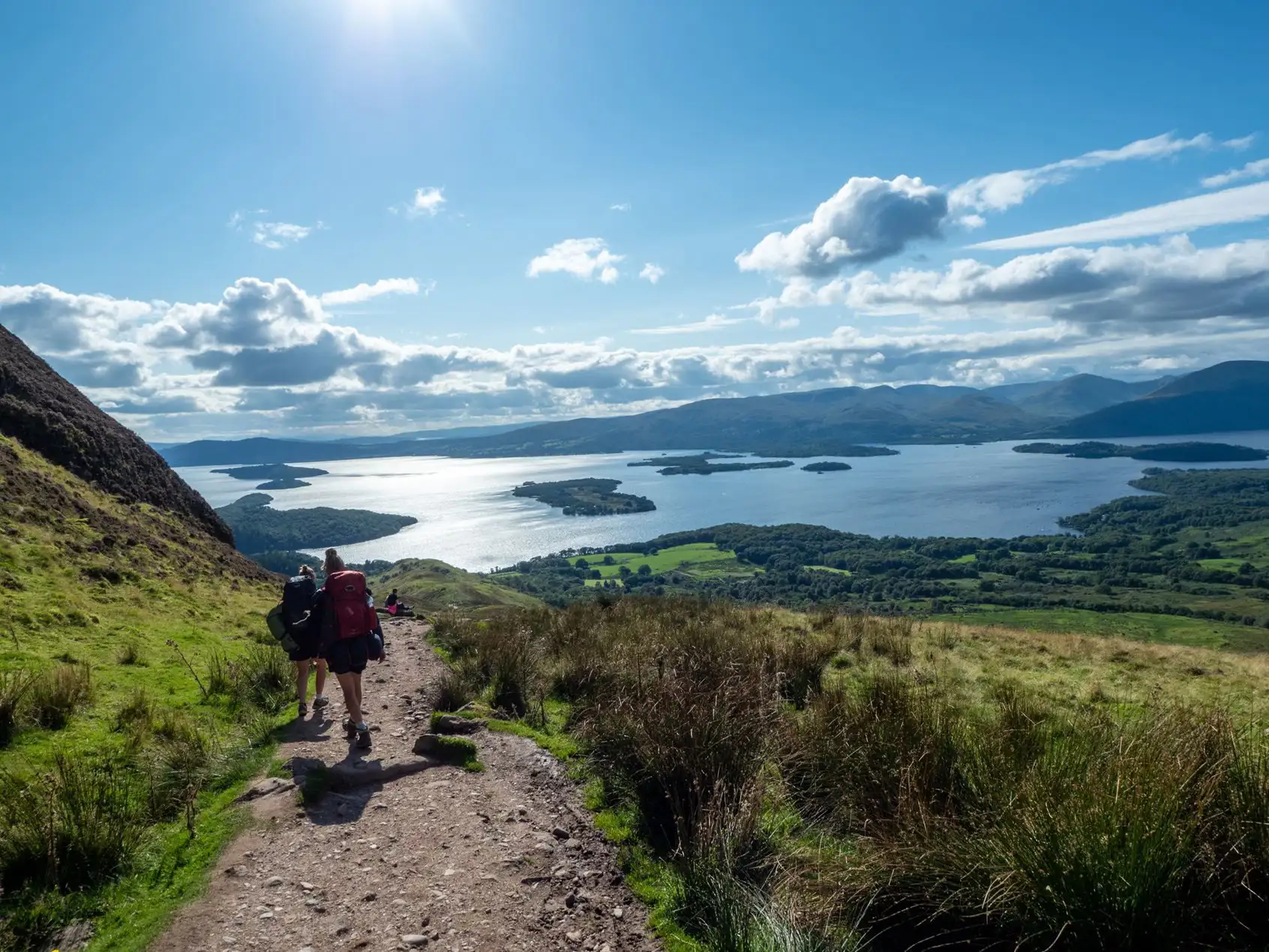 Wandelaars lopen omlaag naar een loch in Schotland.