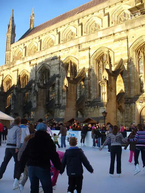 Mensen schaatsen op de ijsbaan op de kerstmarkt in Winchester naast de kathedraal van Winchester.