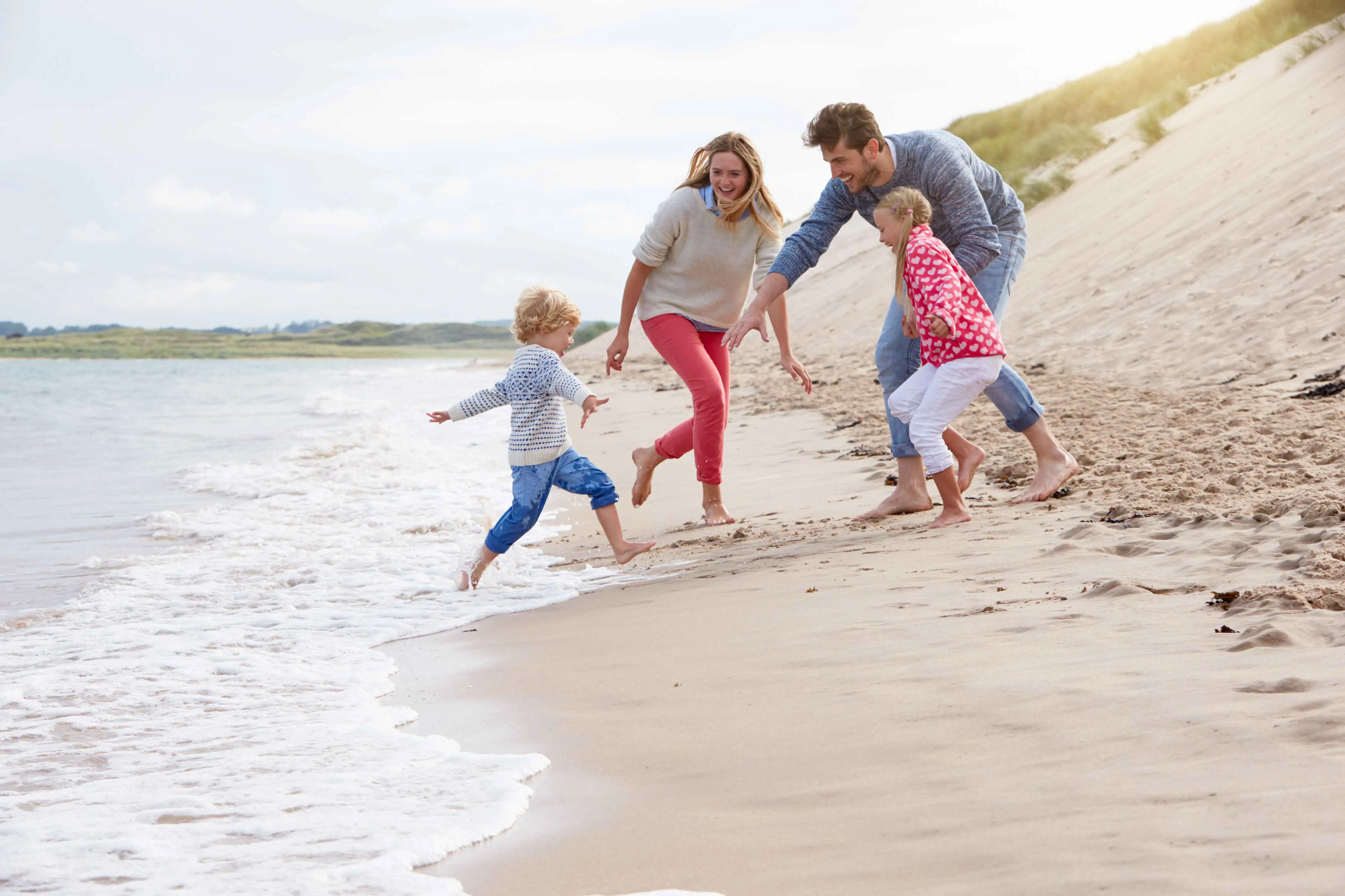 A family playing together on the beach, laughing and enjoying the sand and waves.