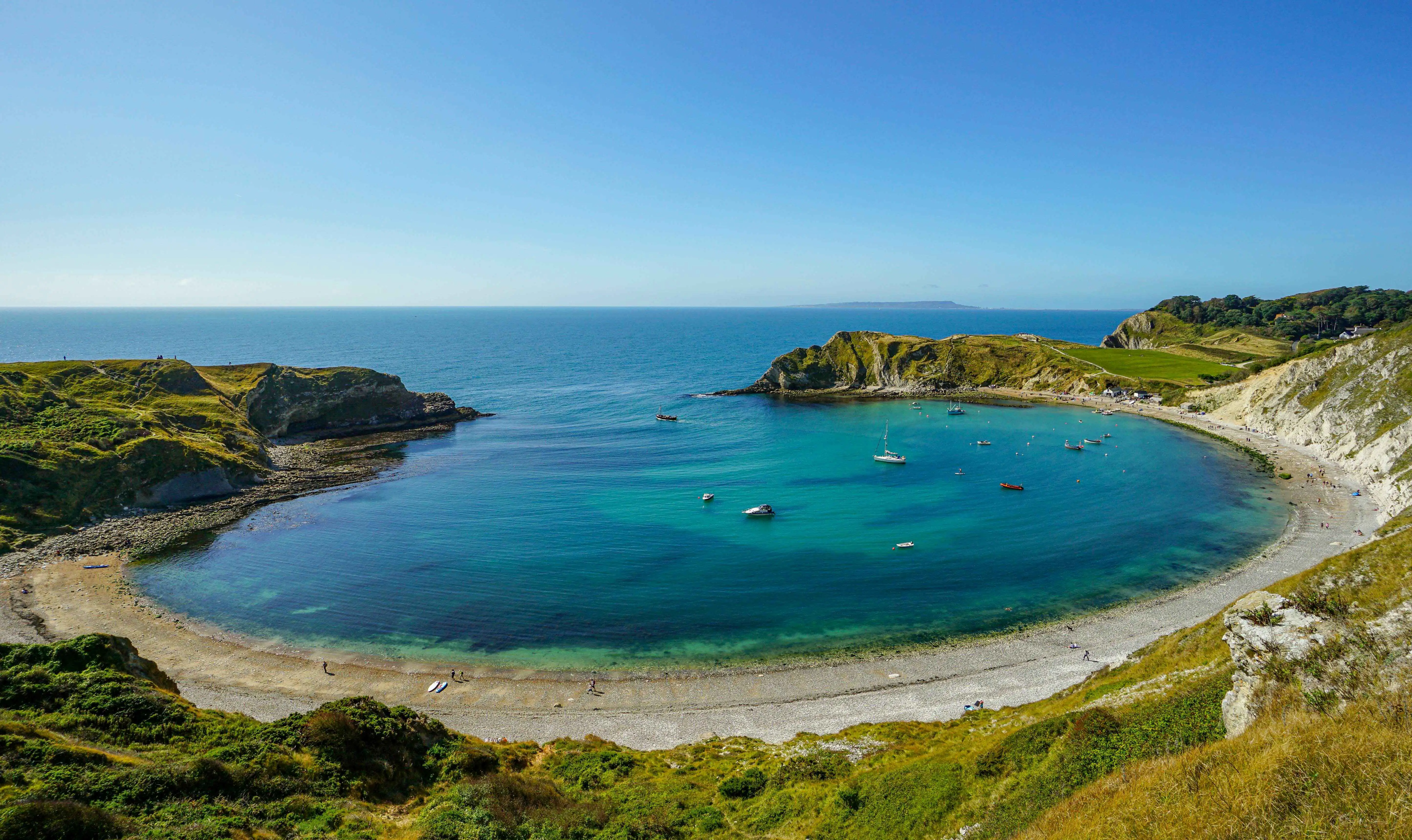 Une vue plongeante sur Lulworth Cove qui met en valeur sa baie et le vaste océan au-delà.