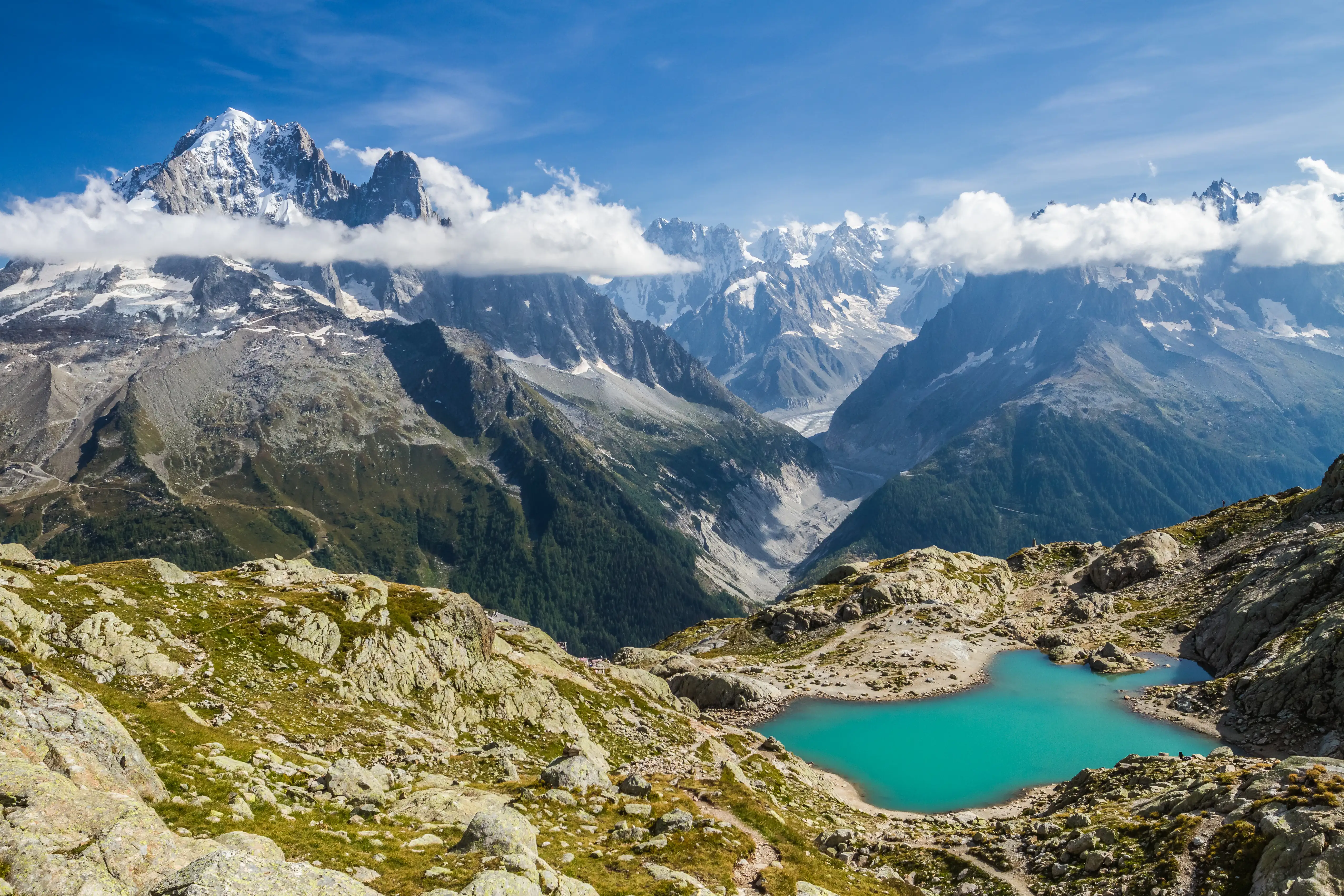 Mont Blanc range and glacier seen from across a valley with a mountain lake in the foreground