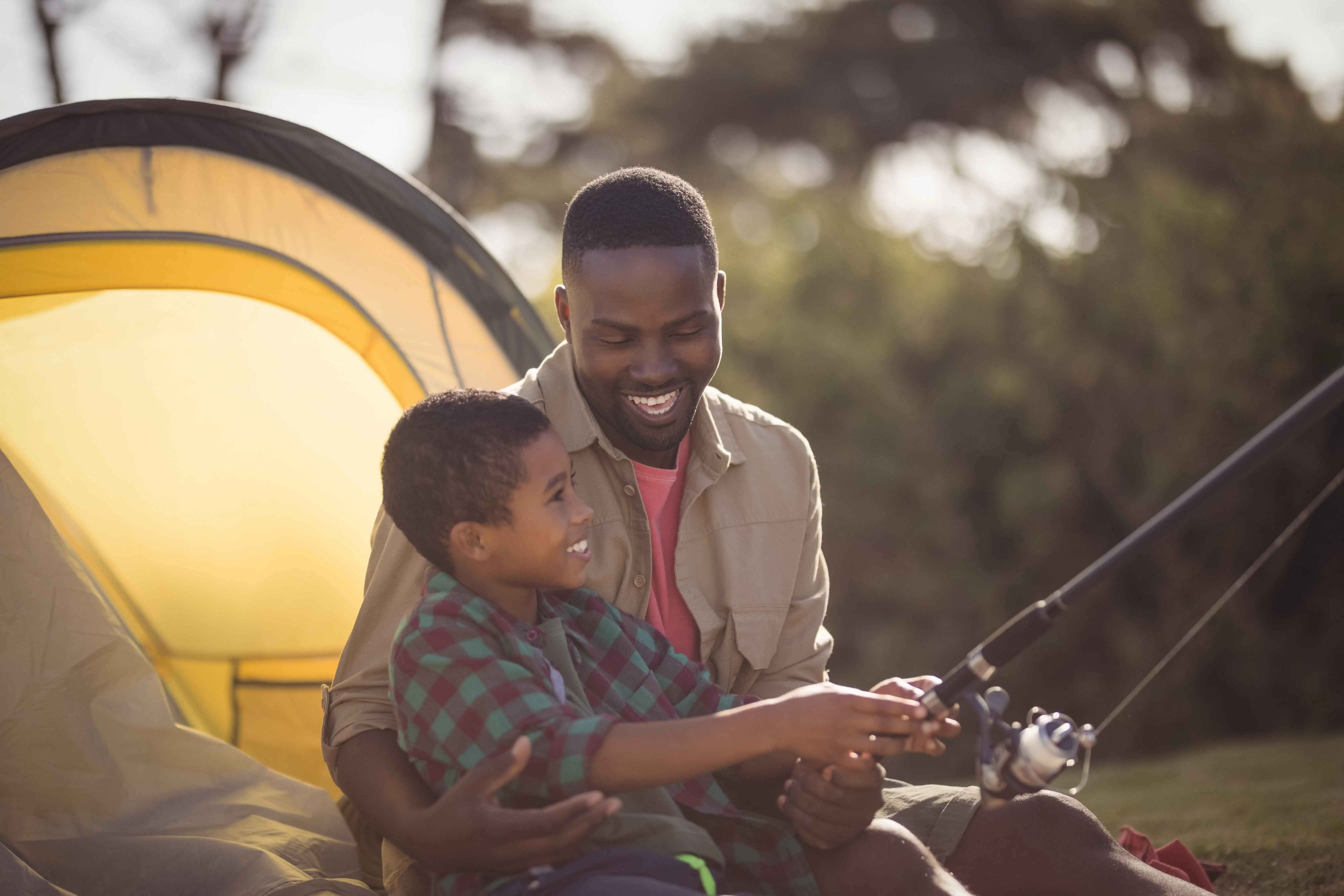 A father and son happily fishing together by the water.