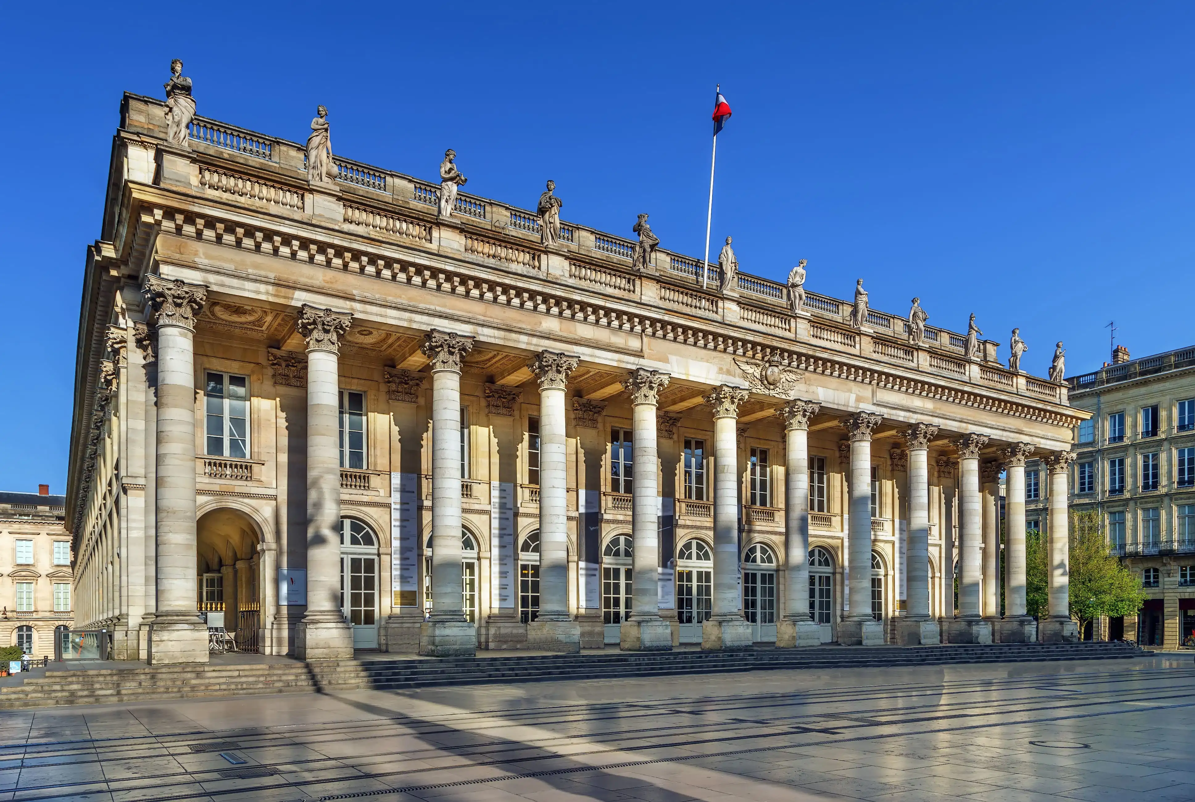 The Grand Théâtre de Bordeaux on a clear day, with neoclassical columns and blue skies above.