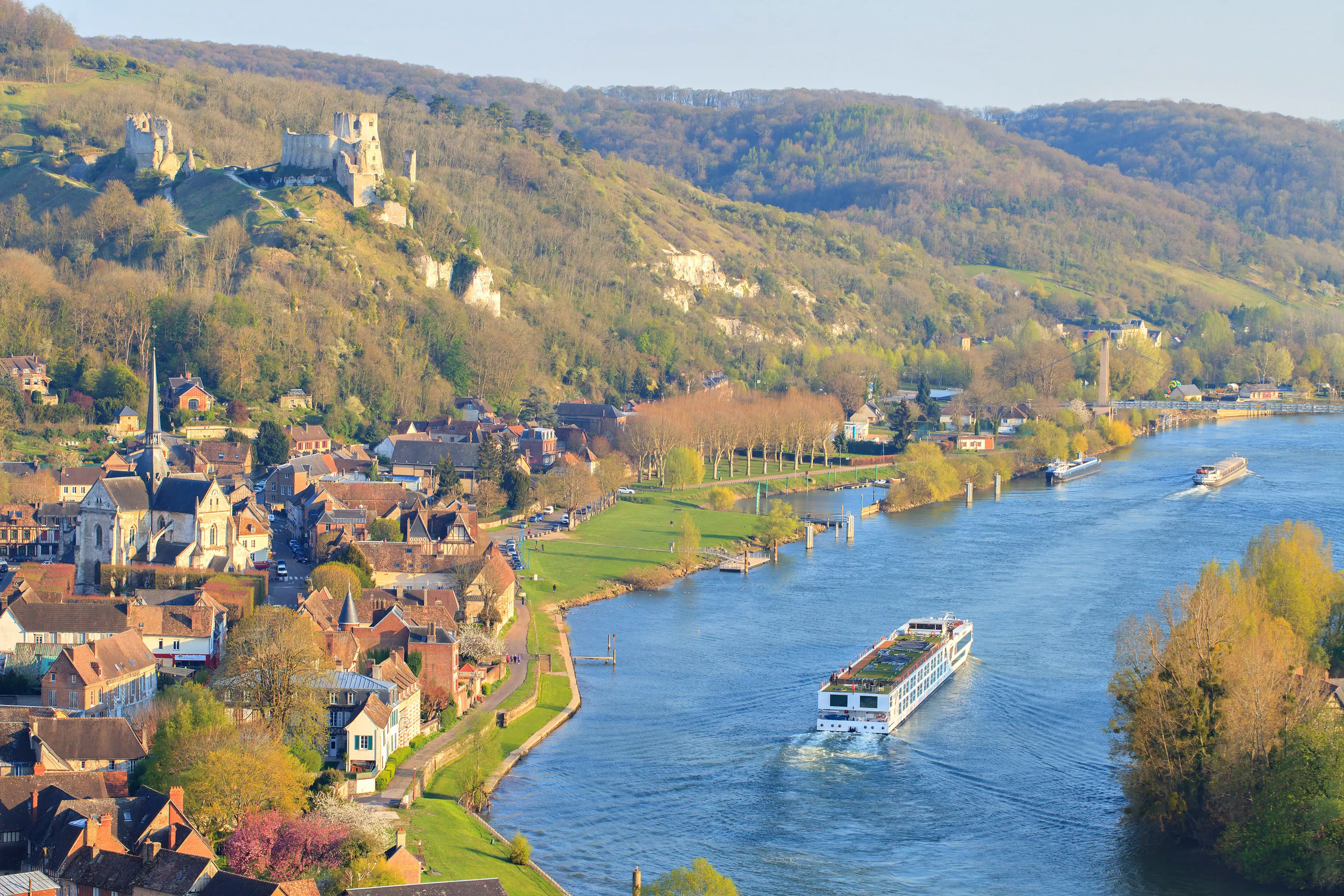 A cruise boat travelling on a wide river past a small town and hilltop castle