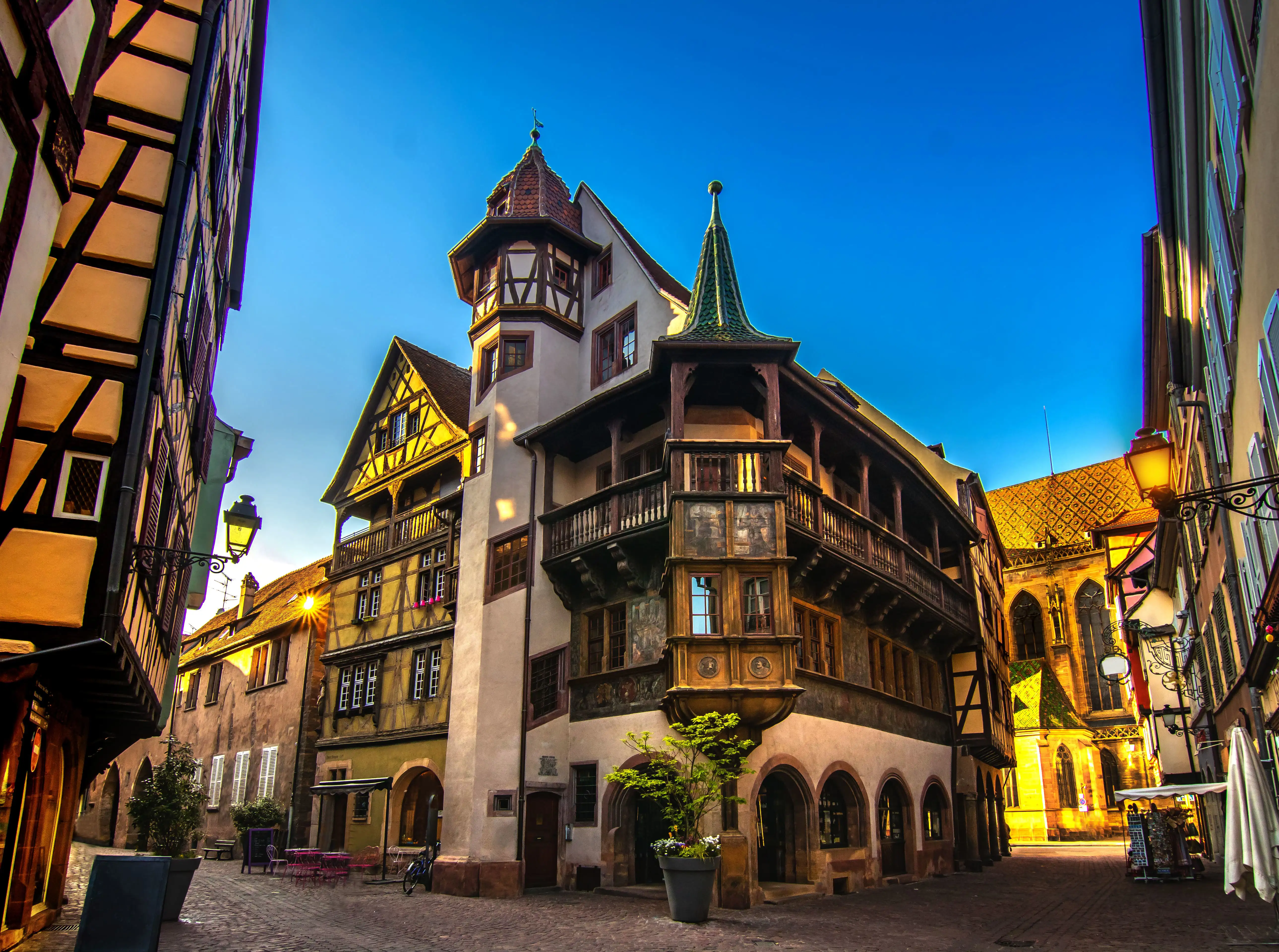 Pfister House in Colmar illuminated by warm evening lights, with timber-framed architecture and soft golden glow.