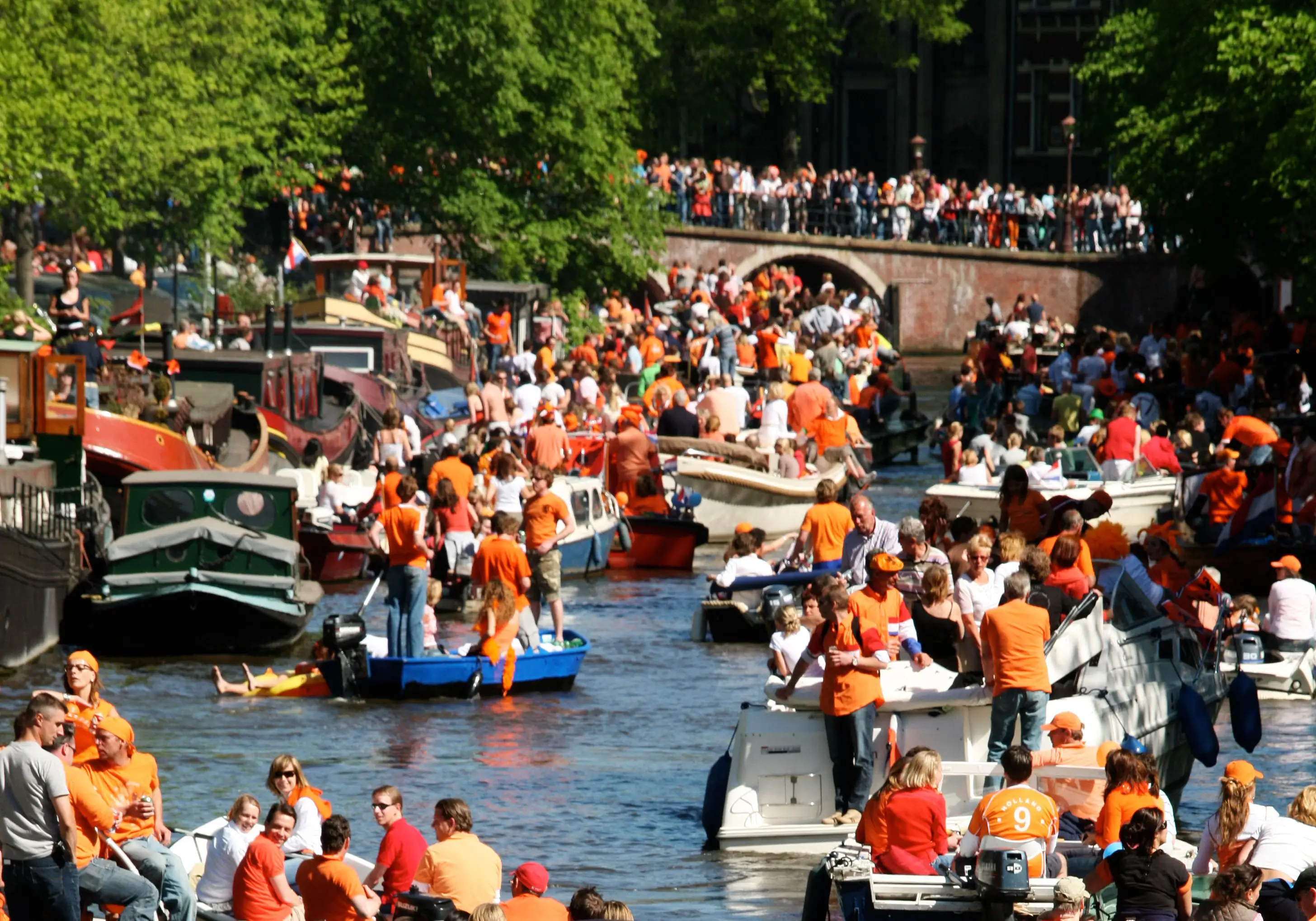 Boats with revellers dressed in orange in Amsterdam.
