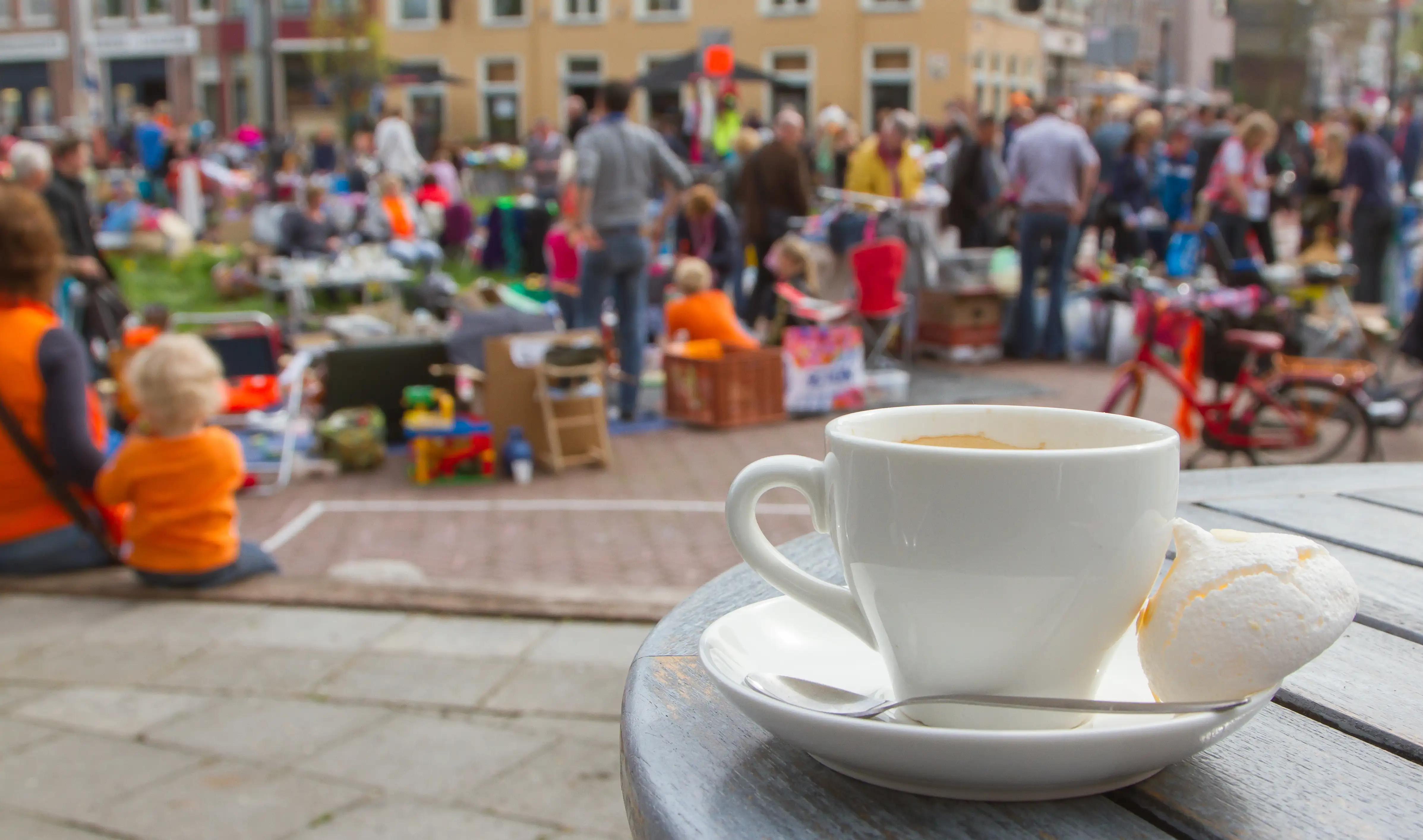 A hot drink sits in the foreground with a blurred flea market in the background.