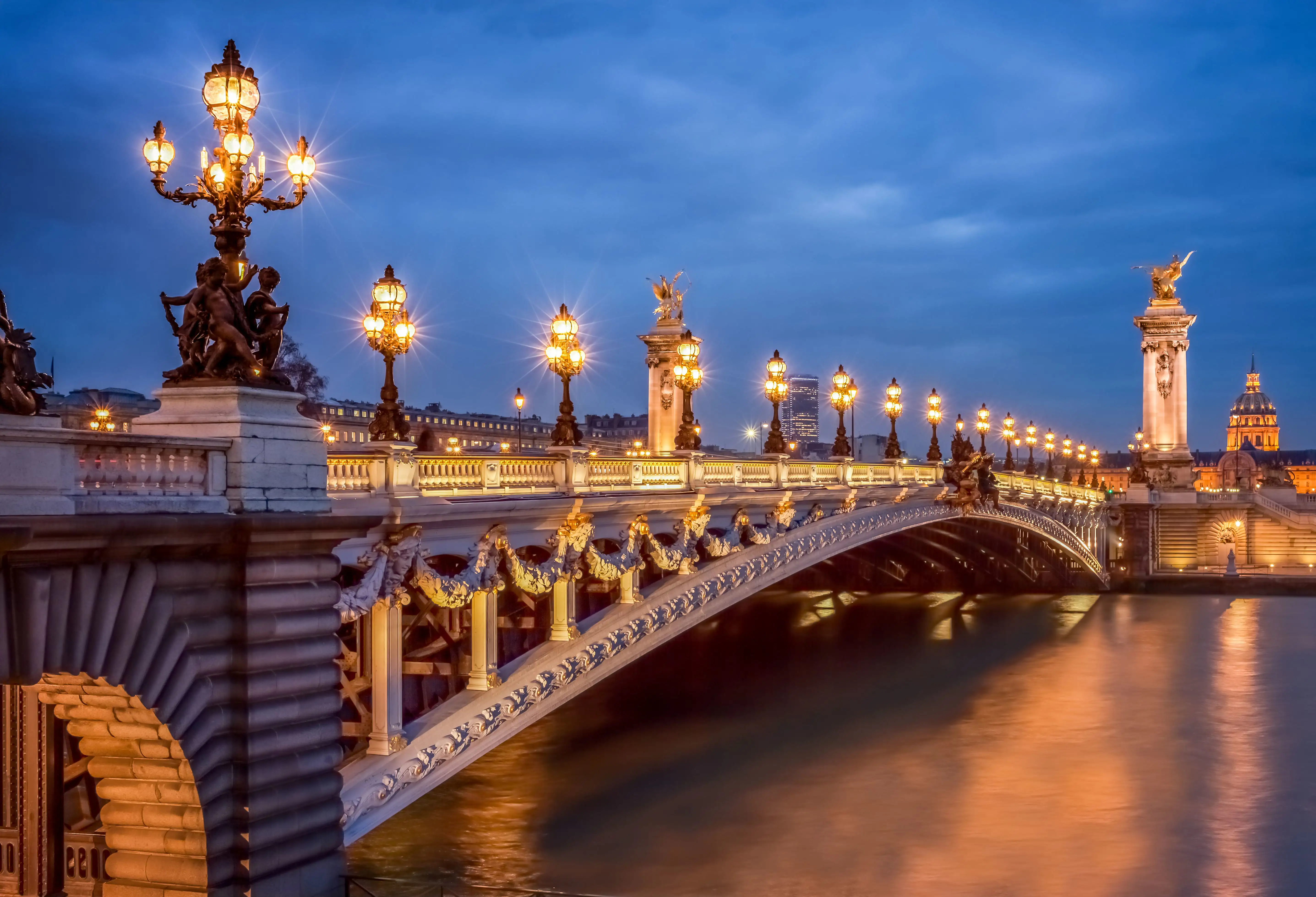 Pont Alexandre III bridge in Paris with ornate street lights illuminated