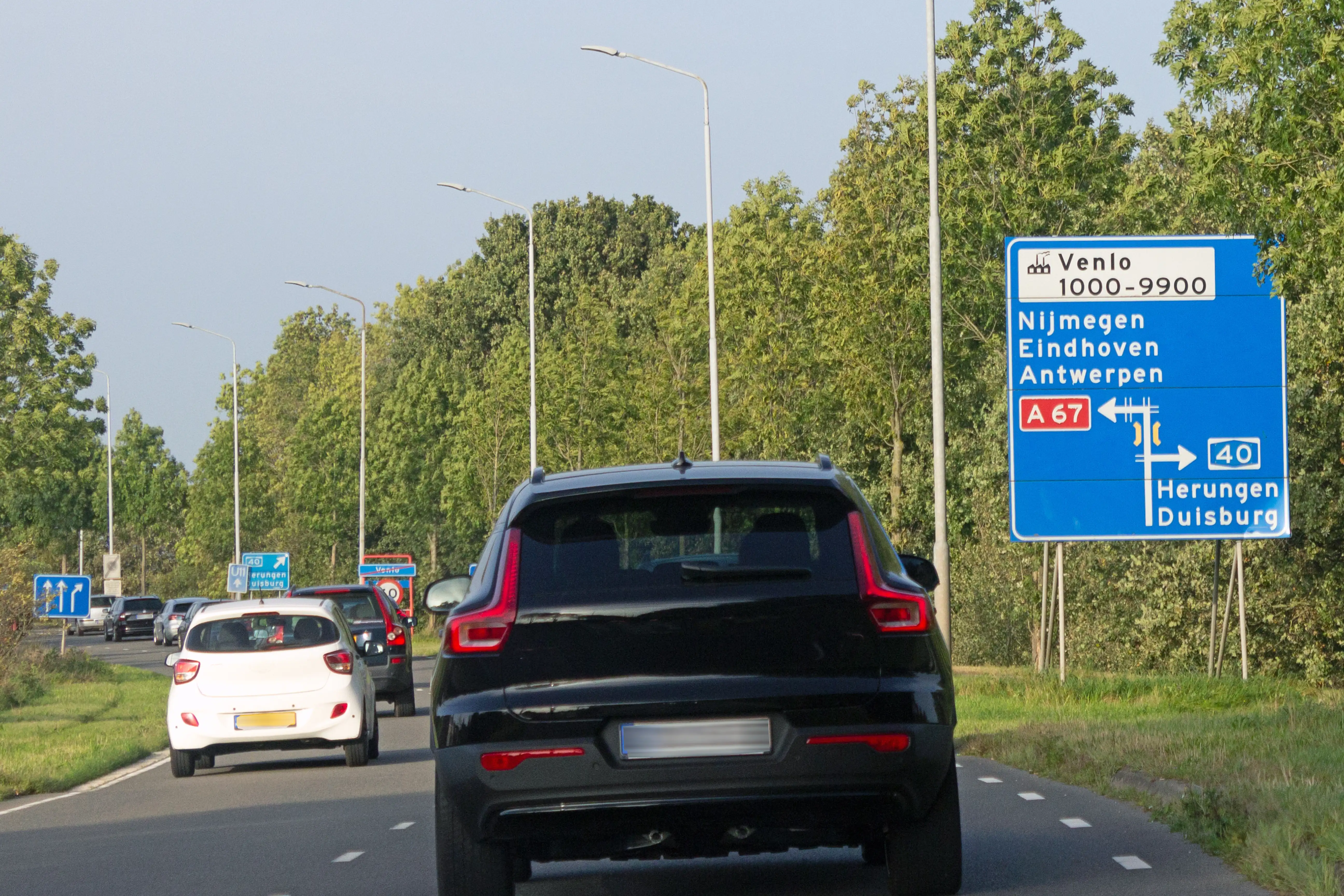 Cars driving on a Dutch road with a road sign showing directions to Nijmegen, Eindhoven and Antwerp